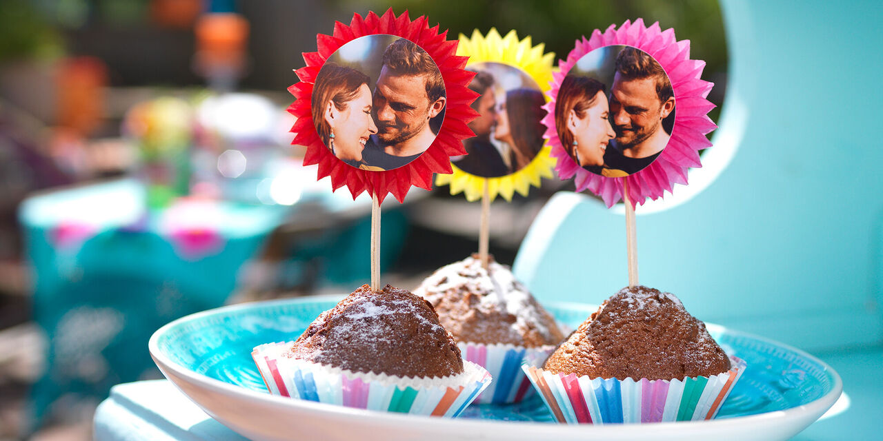 Drei Muffins sind mit Fotosteckern versehen, die ein Foto des Paares zeigen.