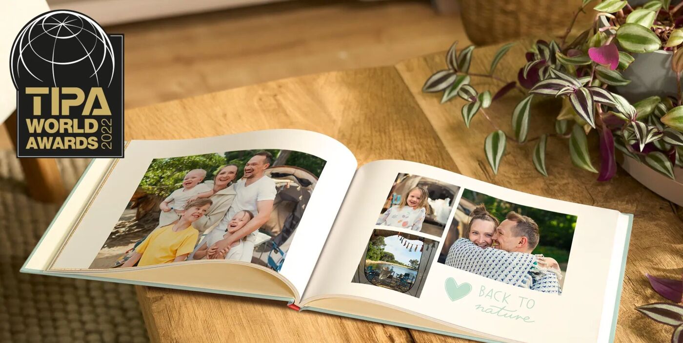 Ein CEWE FOTOBUCH öffnet sich auf einem Tisch, mit fröhlichen Familienbildern und der Aufschrift „BACK TO NATURE“