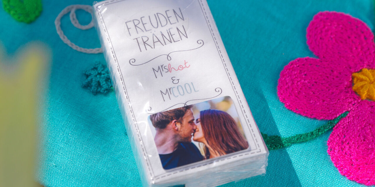 Eine Taschentuchpackung mit der Aufschrift "Freudentränen Mrs. Hot & Mr. Cool", verschönert mit einem Foto des Paares.