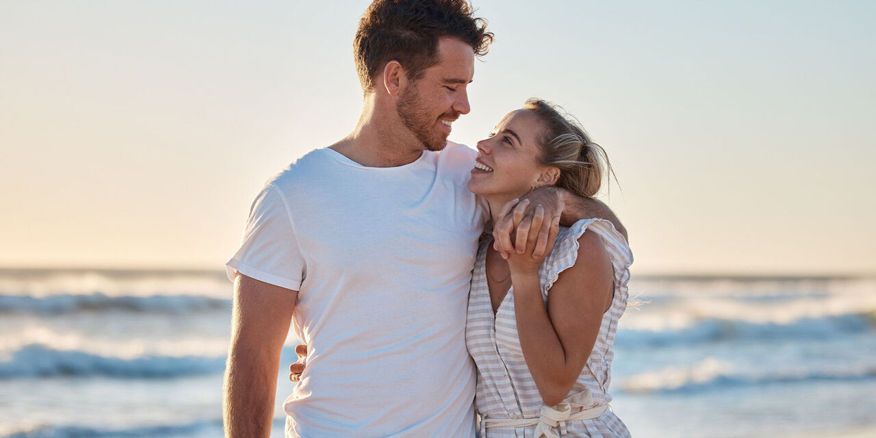 Paar steht am Strand und erfreut sich am Sonnenuntergang