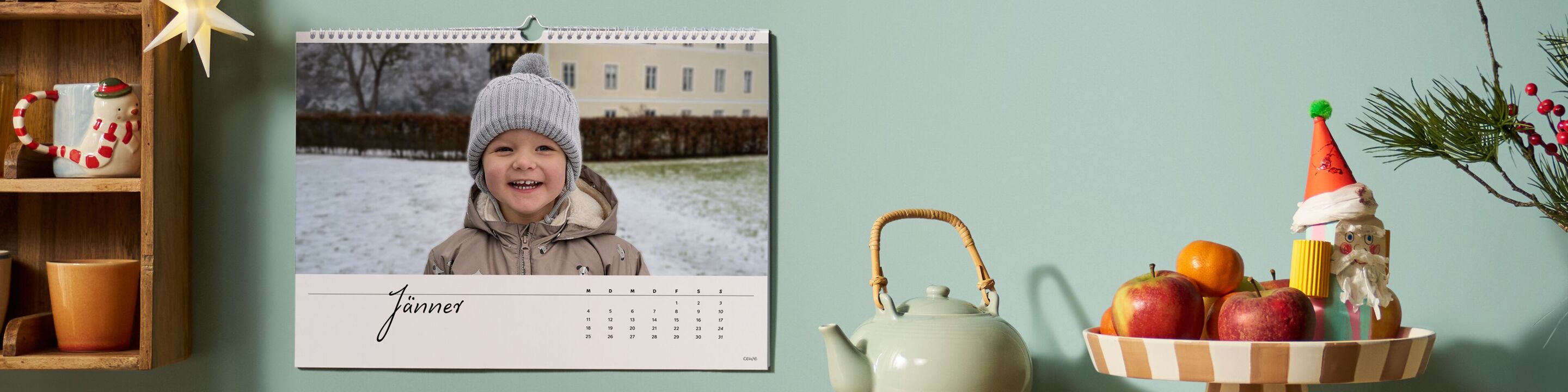 Ein fröhliches Kind mit einer Mütze im Schnee lächelt vor einem Wandkalender.