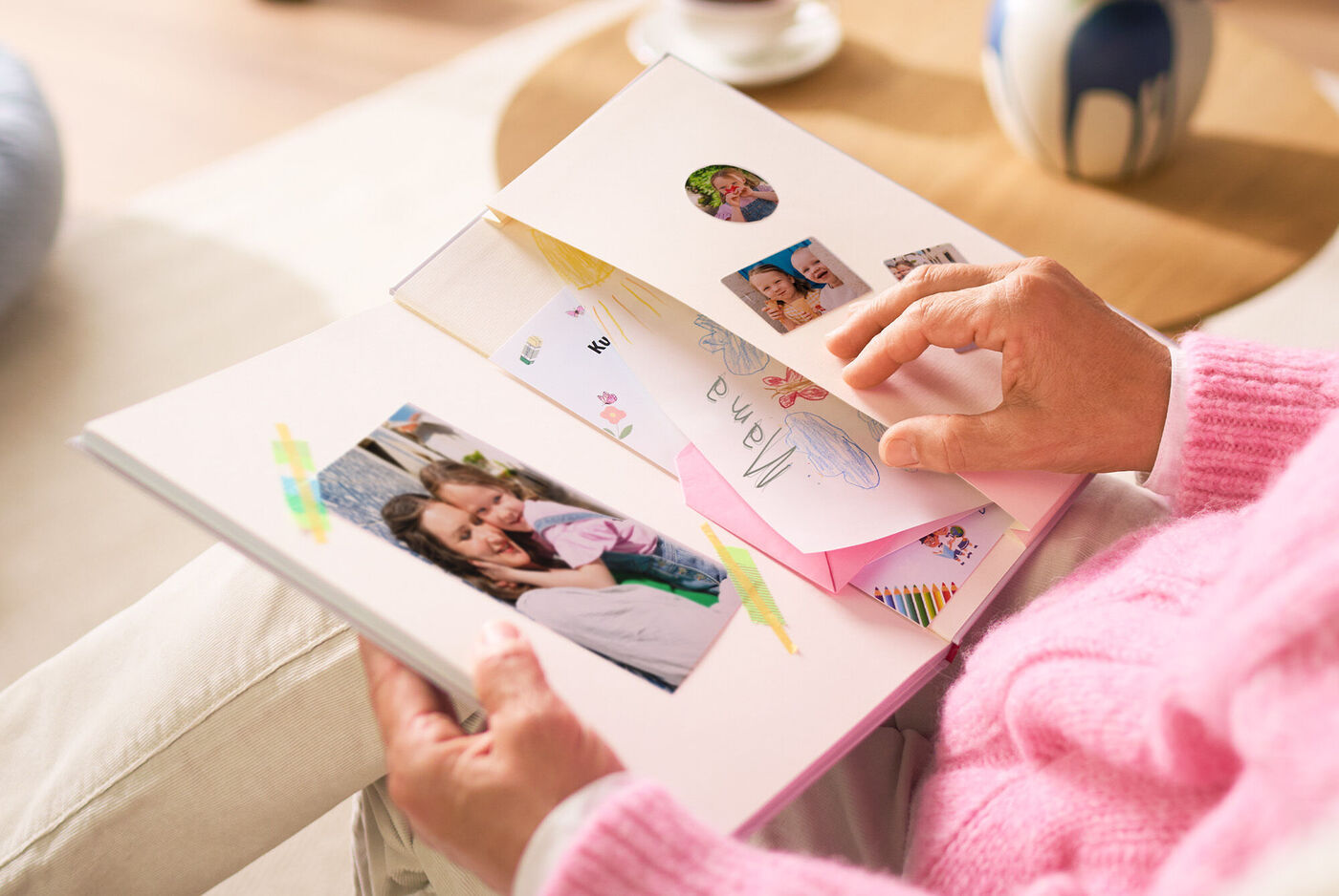 Eine Person blättert durch ein CEWE Fotobuch mit glücklichen Erinnerungen und Fotos.