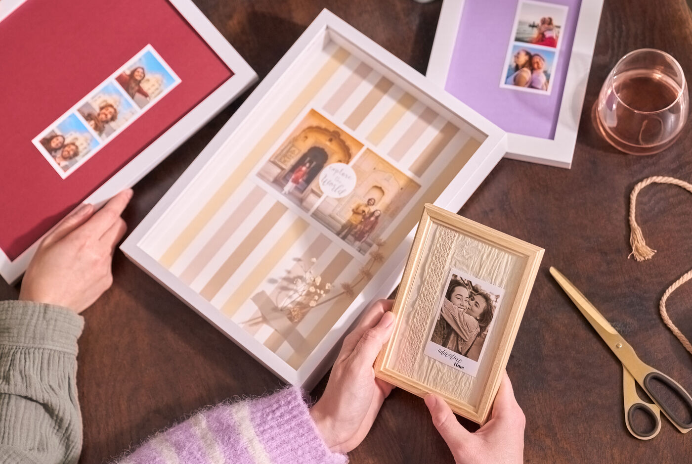 Zwei Frauen sitzen an einem Tisch, vor ihnen liegen vier gerahmte Sofortfotos mit verschiedenen Passepartouts.
