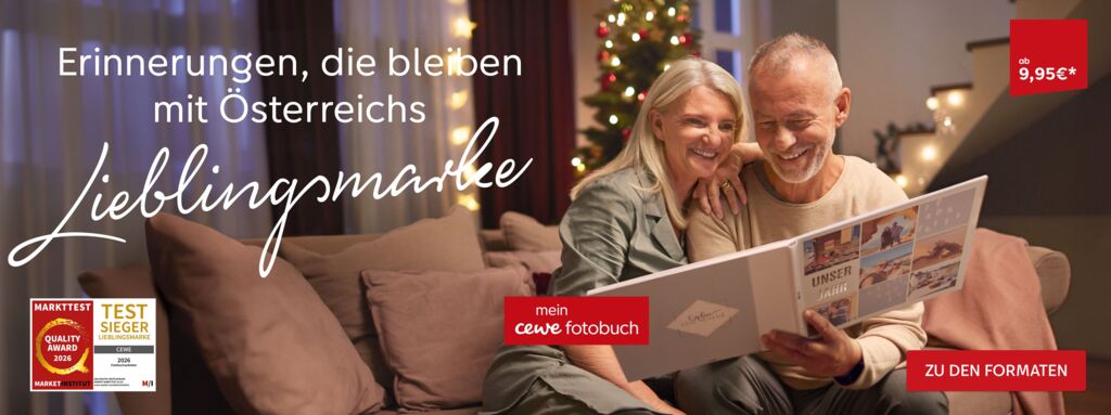 Ein Paar betrachtet gemeinsam ein CEWE FOTOBUCH und lächelt dabei.