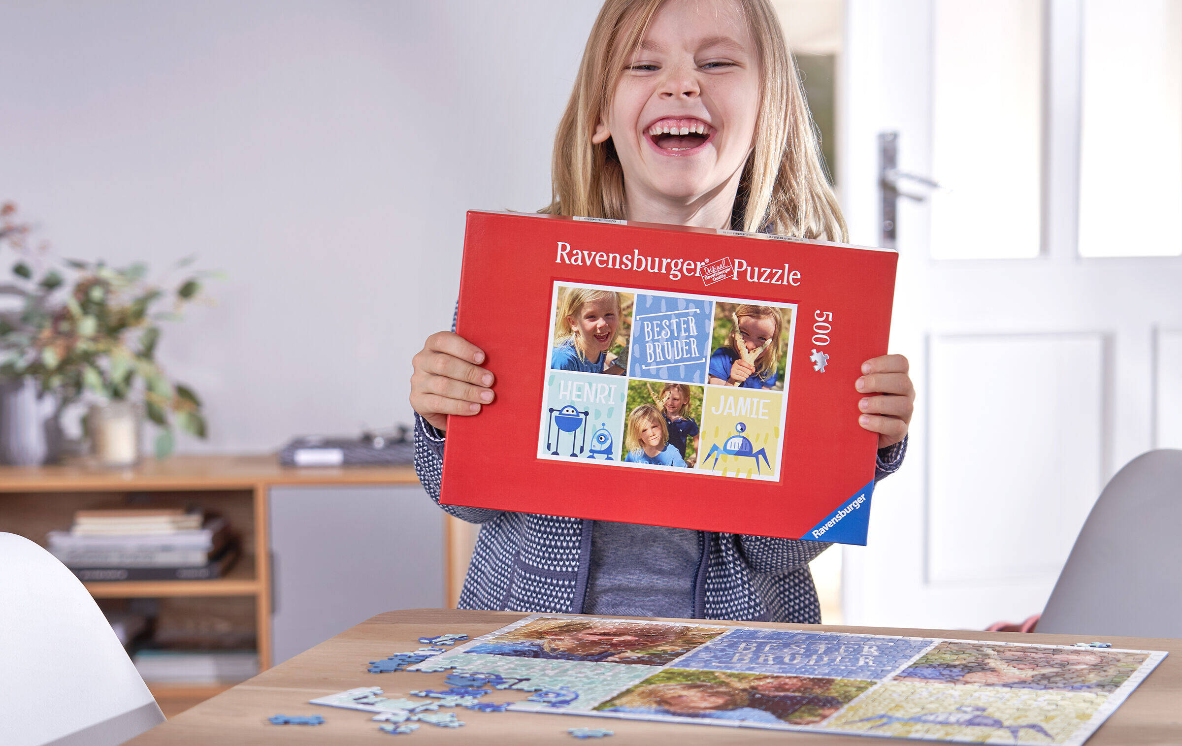 Lachendes Mädchen hält eine Ravensburger-Puzzle-Schachtel in den Händen und zeigt das Motiv.